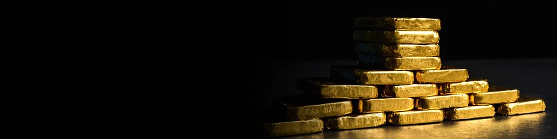 Stacked gold bullion bars in a dark vault