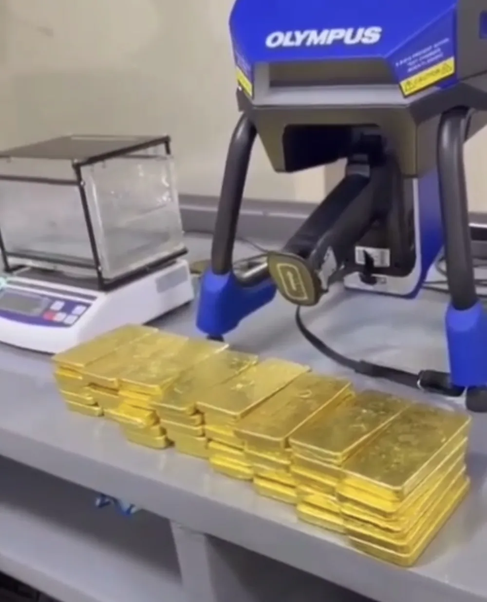 Olympus benchtop XRF analyzer with stacked gold bars and precision scale